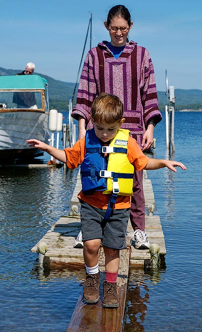 Noah and Anne walking the plank to get off the motor boat; Lake Champlain, VT
