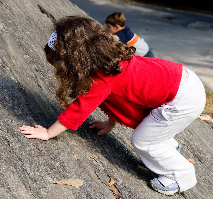 Shayna climbing a big rock in Central Park; New York City; NY; USA