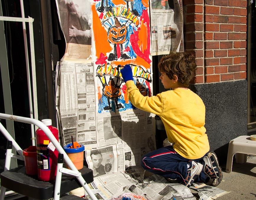 Eytan painting a store window for Halloween; Newton; MA; US