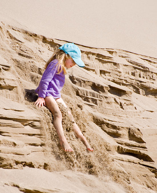 Caroline sliding down sand dunes; Point Reyes; CA; US