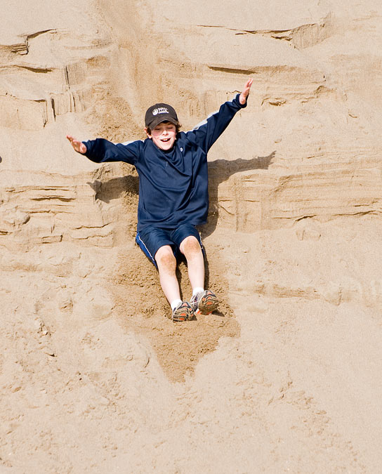 Eytan sliding down a sand dune; Point Reyes; CA; US