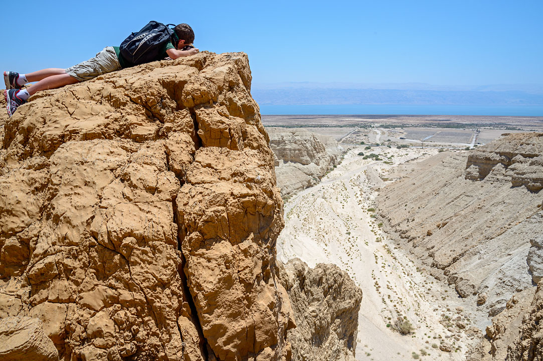 Eytan crawling to the edge to take a picture looking down into the valley; Qumran; MA; Israel